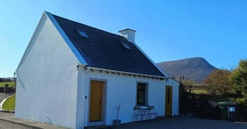 a small white chapel with a mountain in the background at The WEE HOUS Cresslough in Creeslough
