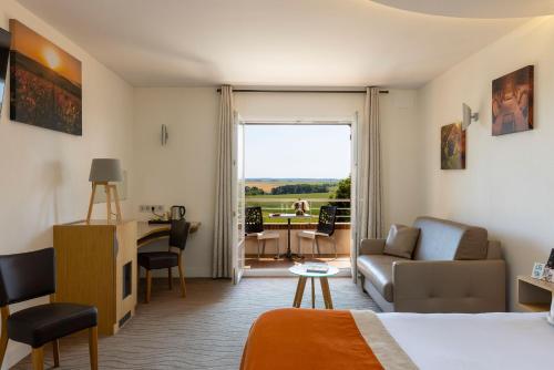 a hotel room with a bed and a living room at LE VAL MORET Hôtel Restaurant et Spa in Magnant