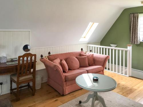 a living room with a pink couch and a table at Goodwood Coach House in Westhampnett