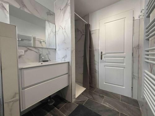 ein Badezimmer mit einem Waschbecken und einer weißen Tür in der Unterkunft Maison neuve 3 chambres à 2 pas de la plage - FR-1-246A-377 in La Michelière