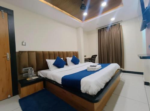 a bedroom with a large bed with blue and white sheets at Hotel Shree Anadi Palace in Ujjain