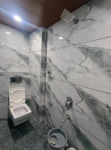 a marble bathroom with a toilet and a sink at Hotel Shree Anadi Palace in Ujjain