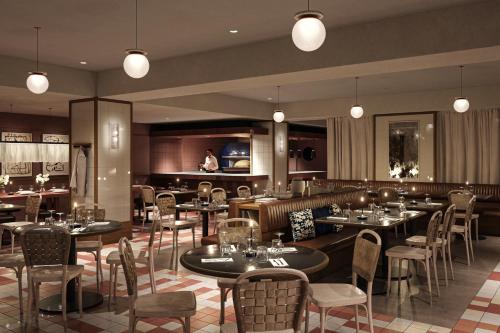 a restaurant with tables and chairs and a waitress at Miiro Spittelberg NEW OPENING in Vienna