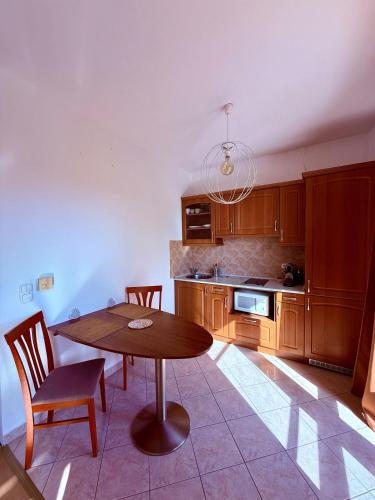 a kitchen with a wooden table and chairs at Beach Apartman by HelloBalatonlelle in Balatonlelle