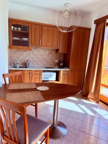 a kitchen with wooden cabinets and a table with chairs at Beach Apartman by HelloBalatonlelle in Balatonlelle