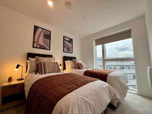 two beds in a bedroom with a large window at Luxury 2 bed Apt Near Ascot & Windsor in Bracknell