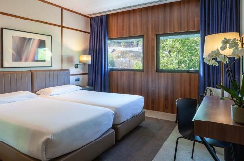 a hotel room with two beds and a desk at Hotel de Guimaraes Business & SPA in Guimarães