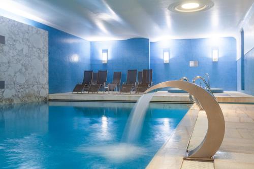 a swimming pool with a fountain in a building at Hotel de Guimaraes Business & SPA in Guimarães