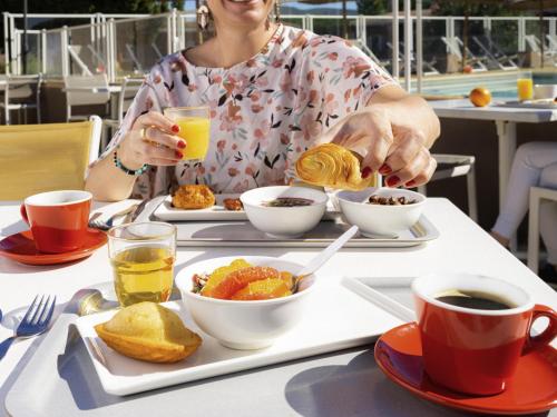 een vrouw aan een tafel met een dienblad met eten bij ibis Montélimar Nord in Saulce-sur-Rhône