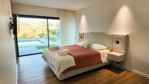 een slaapkamer met een bed en een groot raam bij Casa Encosta do Monte in Póvoa de Lanhoso