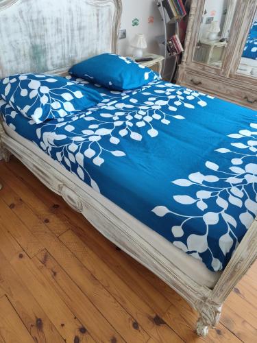 a bed with a blue blanket with white flowers on it at Luna in La Coquille