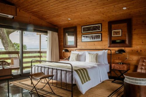 a bedroom with a bed and a large window at Rhino and River Wildlife Retreat & Spa, Pobitora - Guwahati in Pakariāmukh