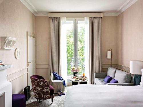 a hotel room with a bed and a couch and a window at Sofitel Le Scribe Paris Opera in Paris