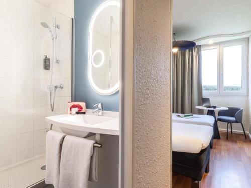 a bathroom with a sink and a bed in a room at ibis Chalons en Champagne in Châlons-en-Champagne