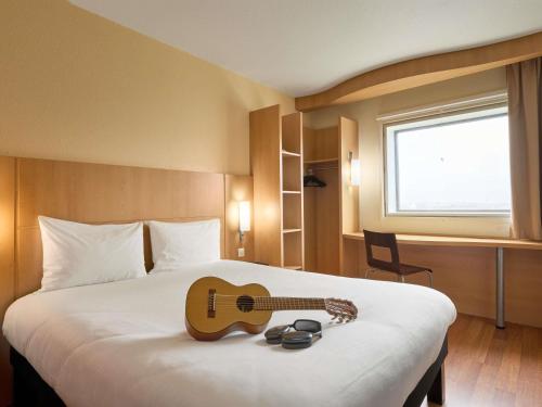 a hotel room with a guitar on a bed at ibis Paris la Défense Esplanade in Courbevoie