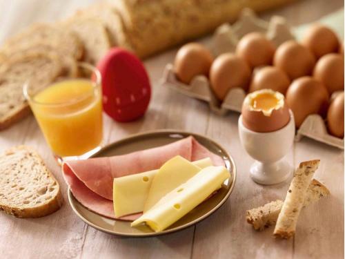 クルブヴォアにあるibis Paris la Défense Esplanadeのチーズと卵とパンの盛り合わせが付いたテーブル