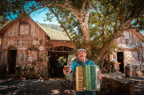 a man playing an accordion in front of a house at Refúgio Rio do Boi in Praia Grande