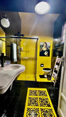 a yellow bathroom with a sink and a toilet at Casa Flores na Janela in Socorro