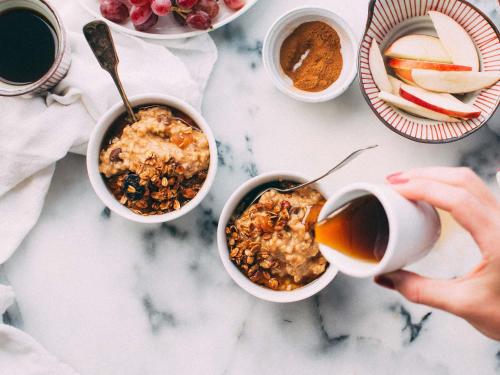 a person holding a cup of coffee next to bowls of food at Grand Hotel Bregenz - MGallery Collection in Bregenz