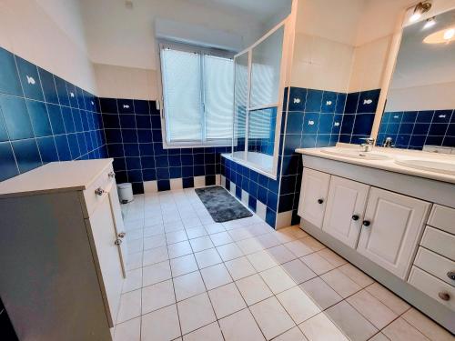 ein Badezimmer mit blauen Fliesen und einer Badewanne und einem Waschbecken in der Unterkunft Villa Ici et Ailleurs, entre mer et forêt in La Tranche-sur-Mer