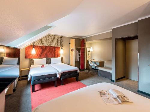 a hotel room with two beds and a desk at ibis Hotel Regensburg City in Regensburg