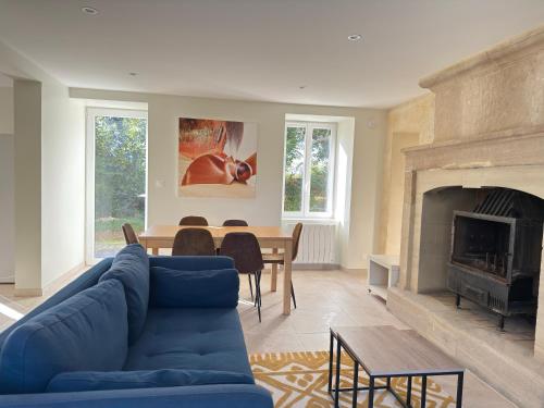 a living room with a blue couch and a fireplace at Le Mesnil in Bayeux