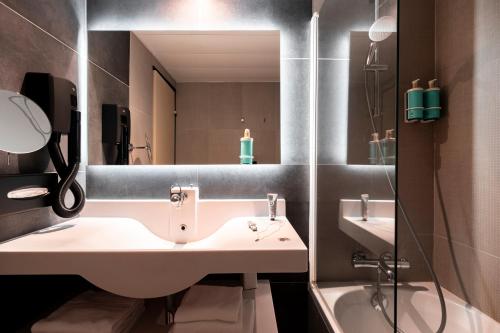 Un baño con lavabo, espejo y bañera. en Novotel Belfort Centre Atria, en Belfort