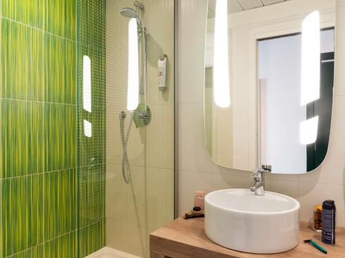 a bathroom with a sink and a glass shower at Ibis Milano Centro in Milan