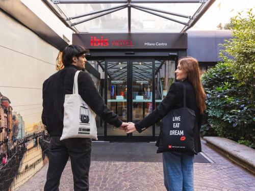 a man and a woman holding hands in front of a store at Ibis Milano Centro in Milan