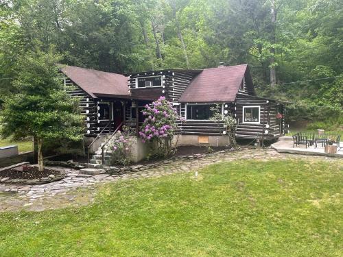 una pequeña cabaña de madera con flores delante en Stony Creek Lodge, en Kahkhout Mountain