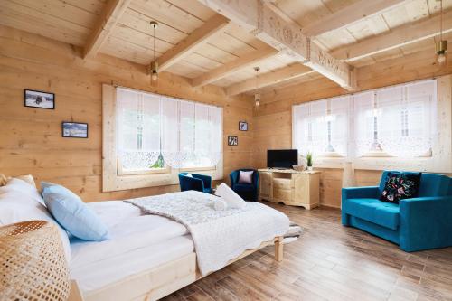 a bedroom with a large white bed and blue chairs at Zasypane Premium House & Sauna in Zakopane by Renters Prestige in Zakopane