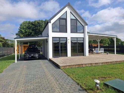 une maison avec une voiture garée devant dans l'établissement Ferienhaus Mila 70qm bis 5 Gäste mit Fass-Sauna, Whirlpool April bis Oktober, 75qm Terrasse und eingezäunten Garten Haustiere willkommen, à Sierosław