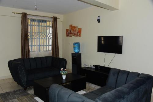 a living room with a couch and a flat screen tv at Zariah Homes in Kakamega