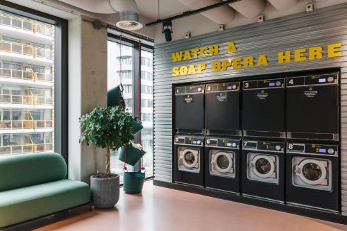 a laundry room with four washing machines and a sign at The Social Hub Eindhoven Extended Stay in Eindhoven