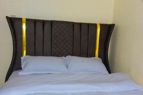 a bed with a black headboard with two white pillows at Zariah Homes in Kakamega