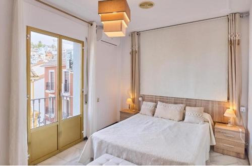 a bedroom with a white bed and a large window at CASA FILO VISTAS MONTAÑa in Rute