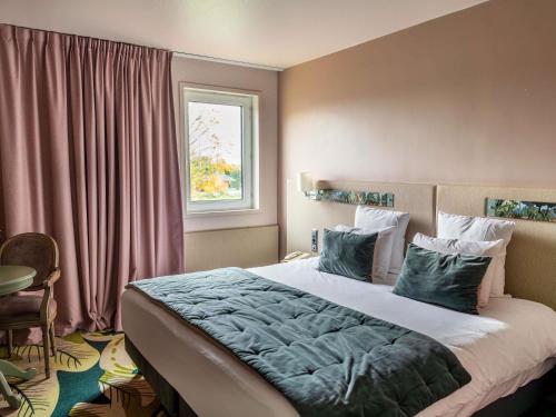 a bedroom with a large bed and a window at Hotel Mercure Parc du Coudray - Barbizon in Le Coudray-Montceaux