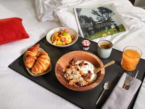 Una bandeja de comida con un desayuno de croissants y un plato de pan. en Hotel Mercure Parc du Coudray - Barbizon, en Le Coudray-Montceaux