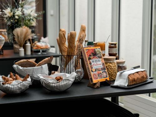 una mesa cubierta con cestas de pan y otros alimentos en Hotel Mercure Parc du Coudray - Barbizon, en Le Coudray-Montceaux