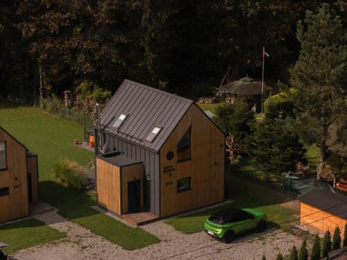 a small house with a green car parked in front of it at Babia Ostoja - domek z balią i sauną in Zawoja