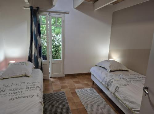 twee bedden in een kamer met een raam bij Gite Lou Bas in Albas