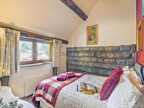 a bedroom with a bed and a stone wall at The Cow Shed - farm cottage close to Stratford in Temple Grafton