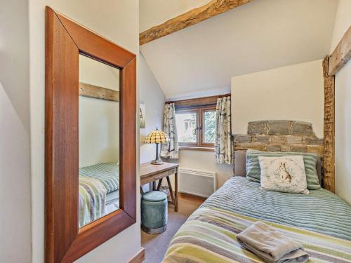 a bedroom with a bed and a mirror at The Cow Shed - farm cottage close to Stratford in Temple Grafton