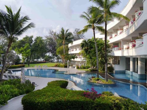 een resort met zwembad en palmbomen bij Novotel Rayong Rim Pae Resort in Klaeng