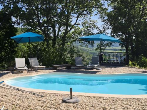 een zwembad met twee parasols en twee stoelen en een tafel en stoelen bij Gite Le Soupadou in Albas