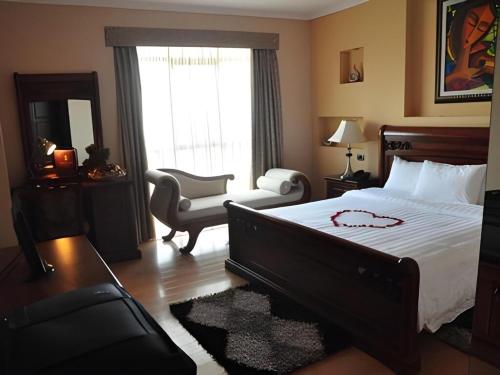 a bedroom with a bed and a chair and a couch at YOD Abyssinia International Hotel and Cultural Restaurant in Addis Ababa