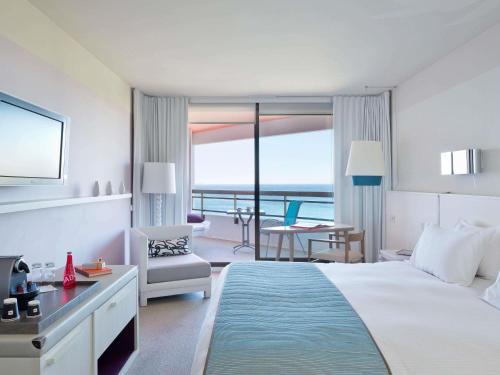 a hotel room with a bed and a view of the ocean at Pullman Cannes Mandelieu in Mandelieu-la-Napoule