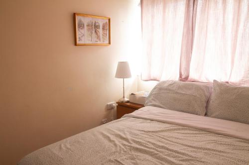 a bedroom with a bed with a window and a lamp at Spacious 4-bedroom Townhouse with Garden- Perfect for Groups! in Sydenham