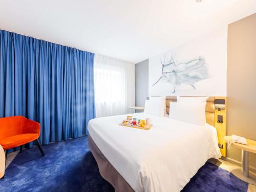 a hotel room with a large bed and a red chair at Mercure Paris Massy Gare TGV in Massy