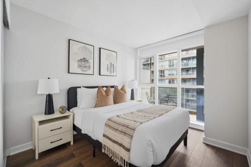 ein weißes Schlafzimmer mit einem Bett und einem Fenster in der Unterkunft Trendy 1BR Condo Free Parking Downtown Toronto in Toronto